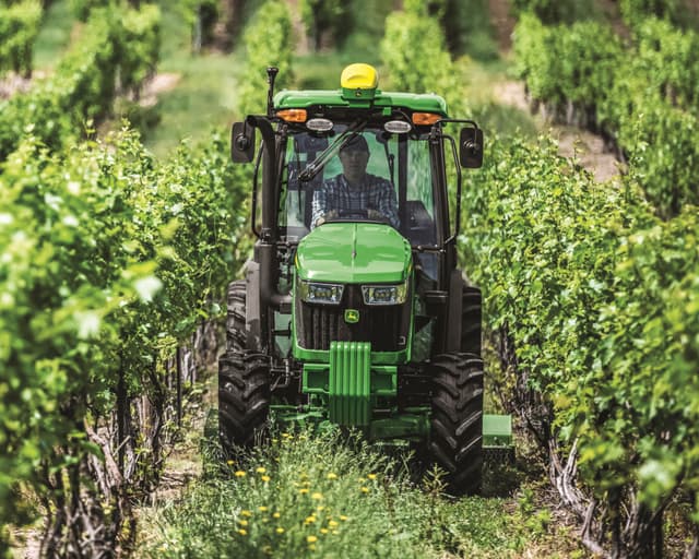 A John Deere 5075EN Narrow Tractor makes its way through a vineyard in California.