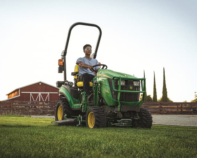 A person operates a John Deere lawn tractor with a 60D mower deck in California.