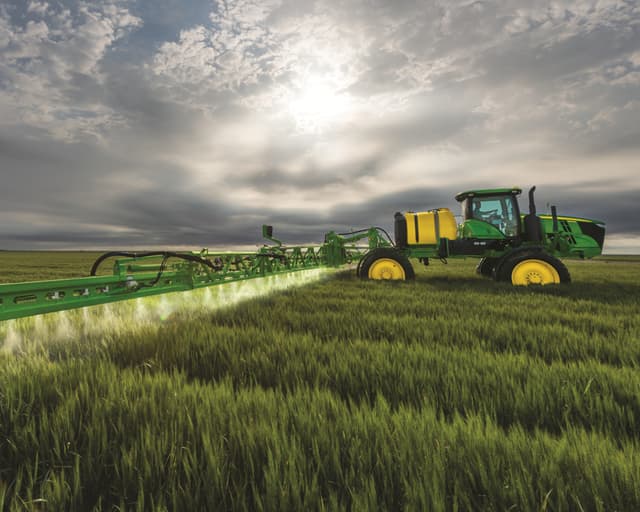 A John Deere sprayer sprays a field in California.