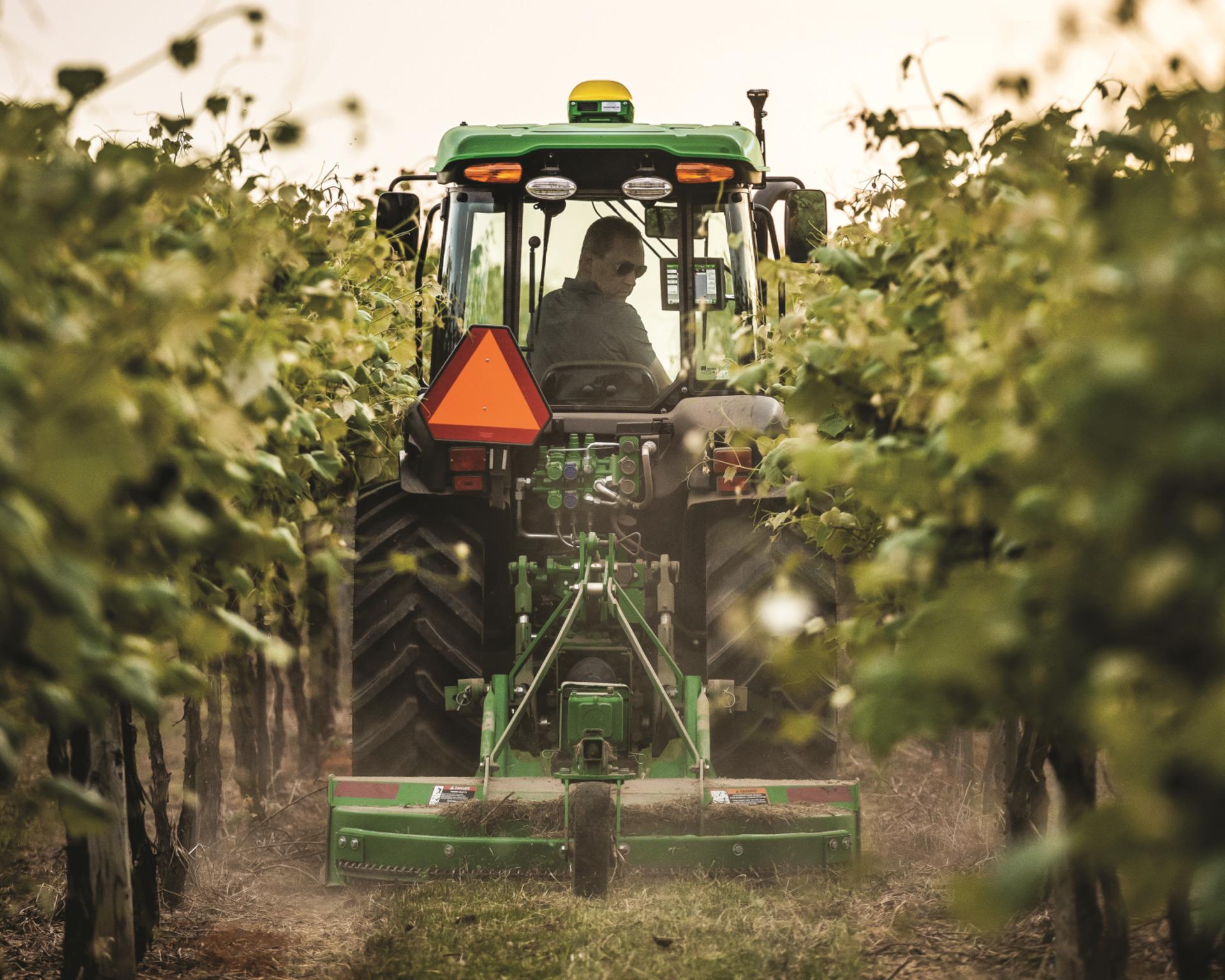 John Deere Compact Tractor with tillage attachment in corn field