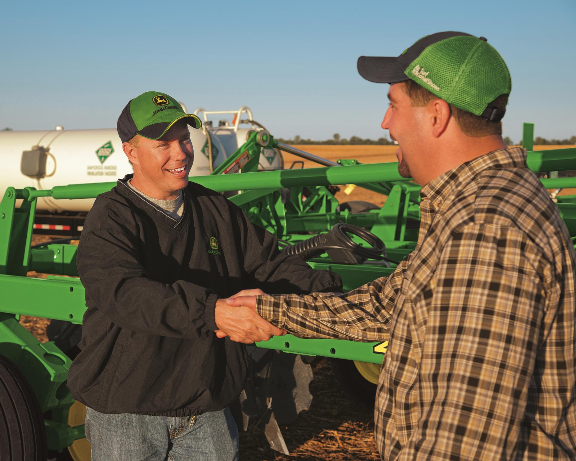two John Deere technicians shake hands
