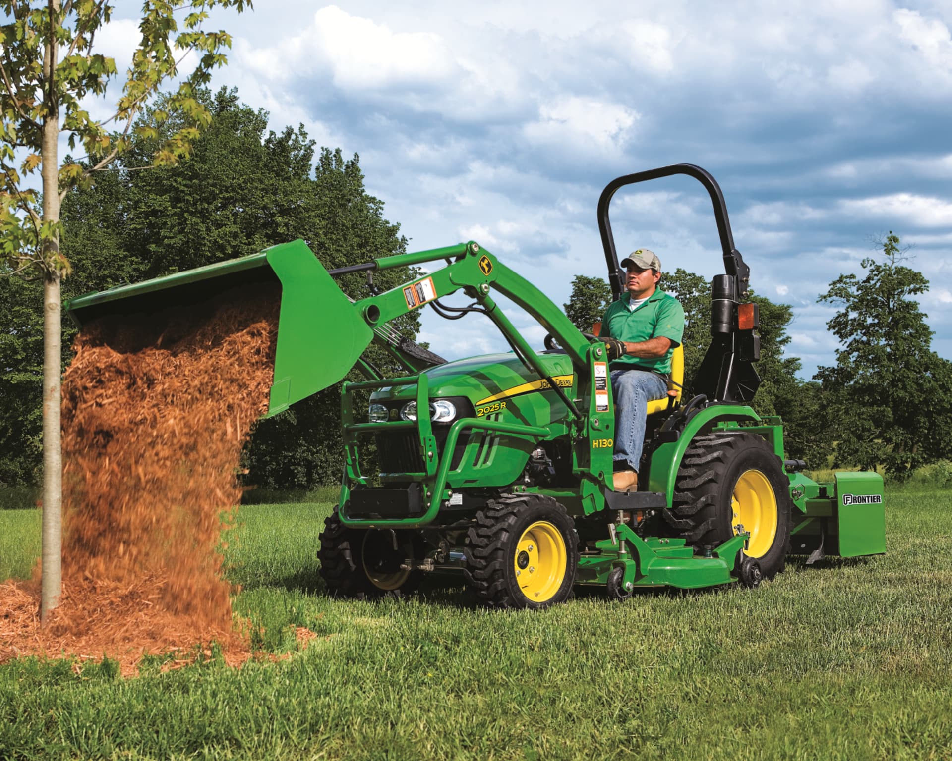 A John Deere 2025R with loader and scraper attachments.
