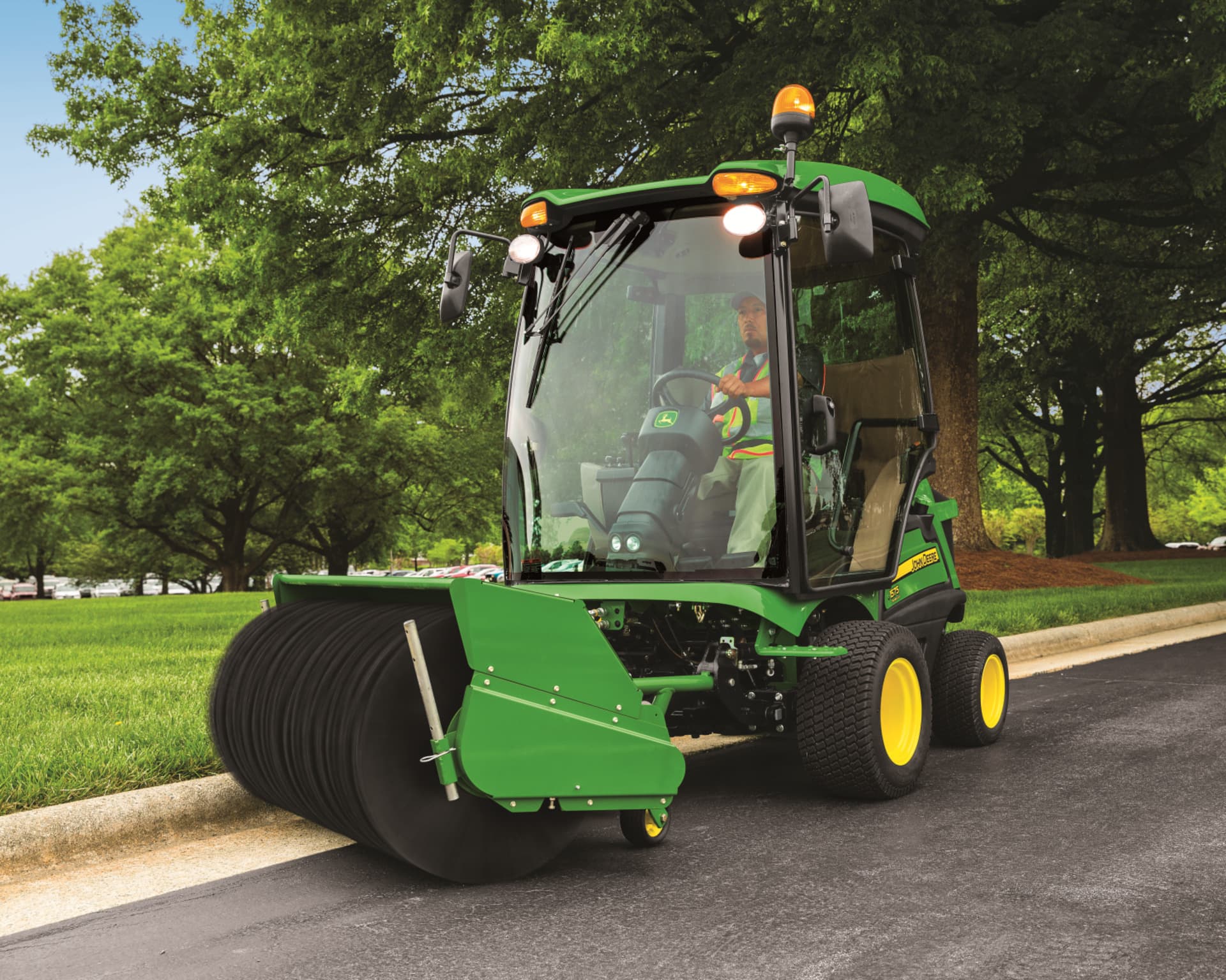 A John Deere 1575 mower with a front sweeping attachment.