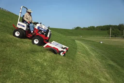 A property manager uses a Ventrac mower to mow a steep hill.