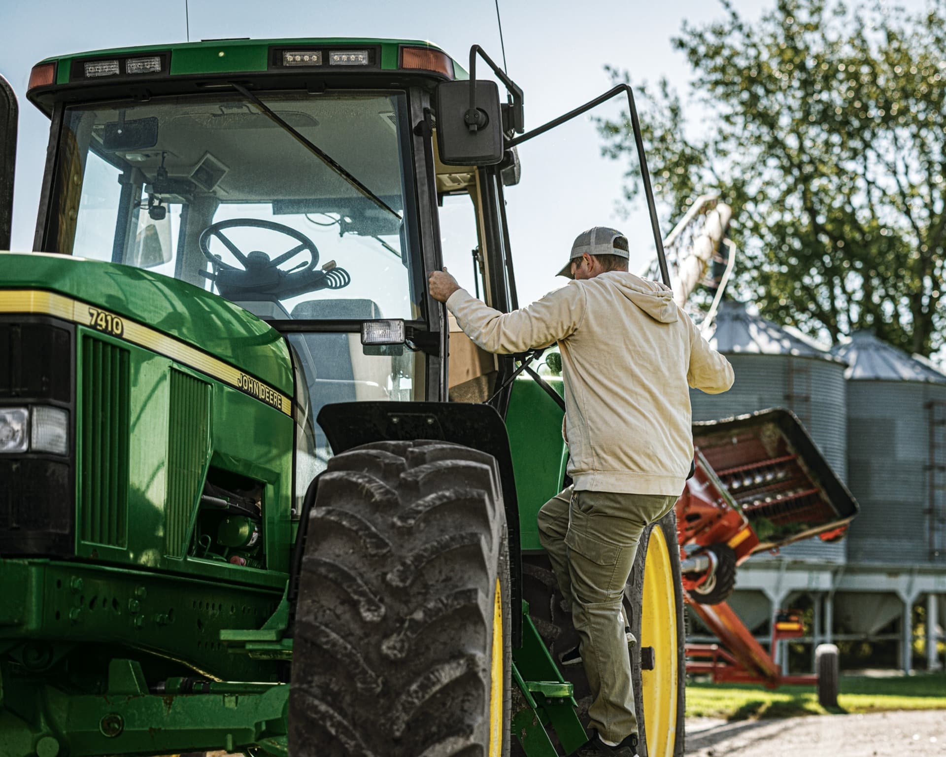 A worker enters a John Deere tractor.