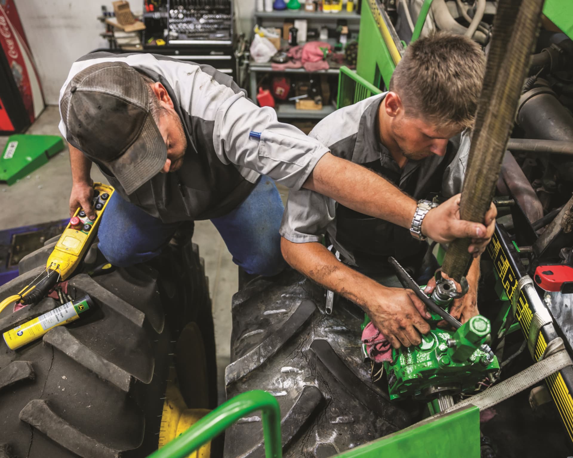 Workers inspect a John Deere machine during a winter service inspection.