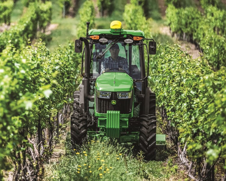 A John Deere 5075EN Narrow Tractor makes its way through a vineyard in California.