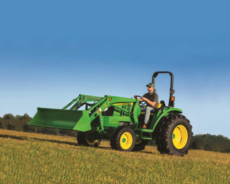 A worker operates a John Deere 4044M for use on their California orchard.