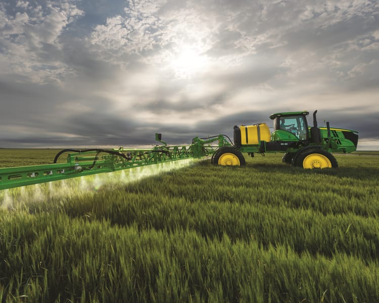 A John Deere sprayer sprays a field in California.