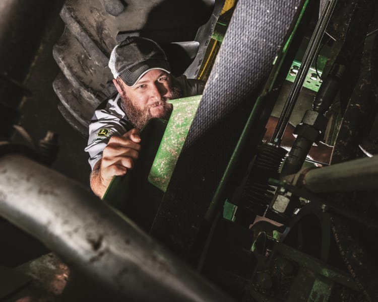 A worker inspects farm equipment during a winter inspection.