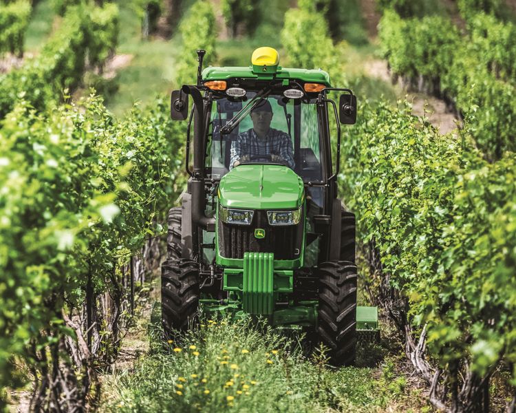 A John Deere 5075EN Narrow Tractor makes its way through a vineyard in California.