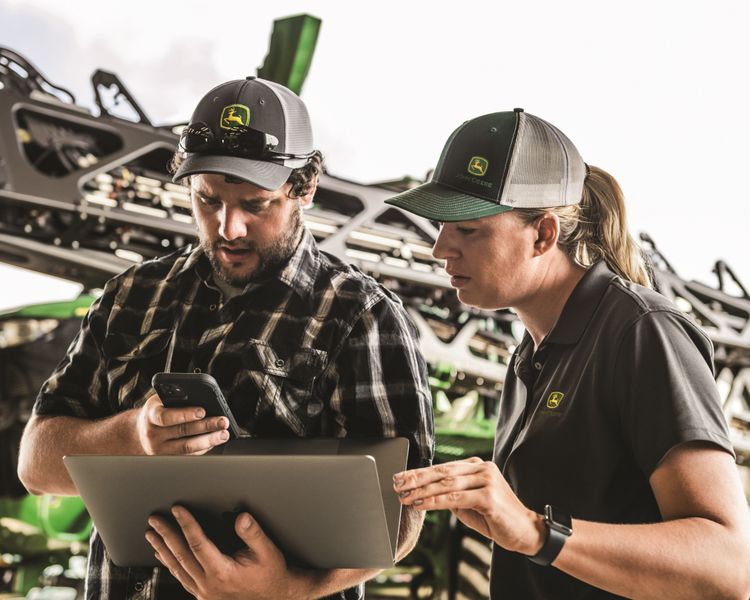 Two workers observe the mobile version of the John Deere Operations Center app.