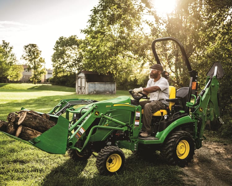 A John Deere 1025R with loader and backhoe attachments.