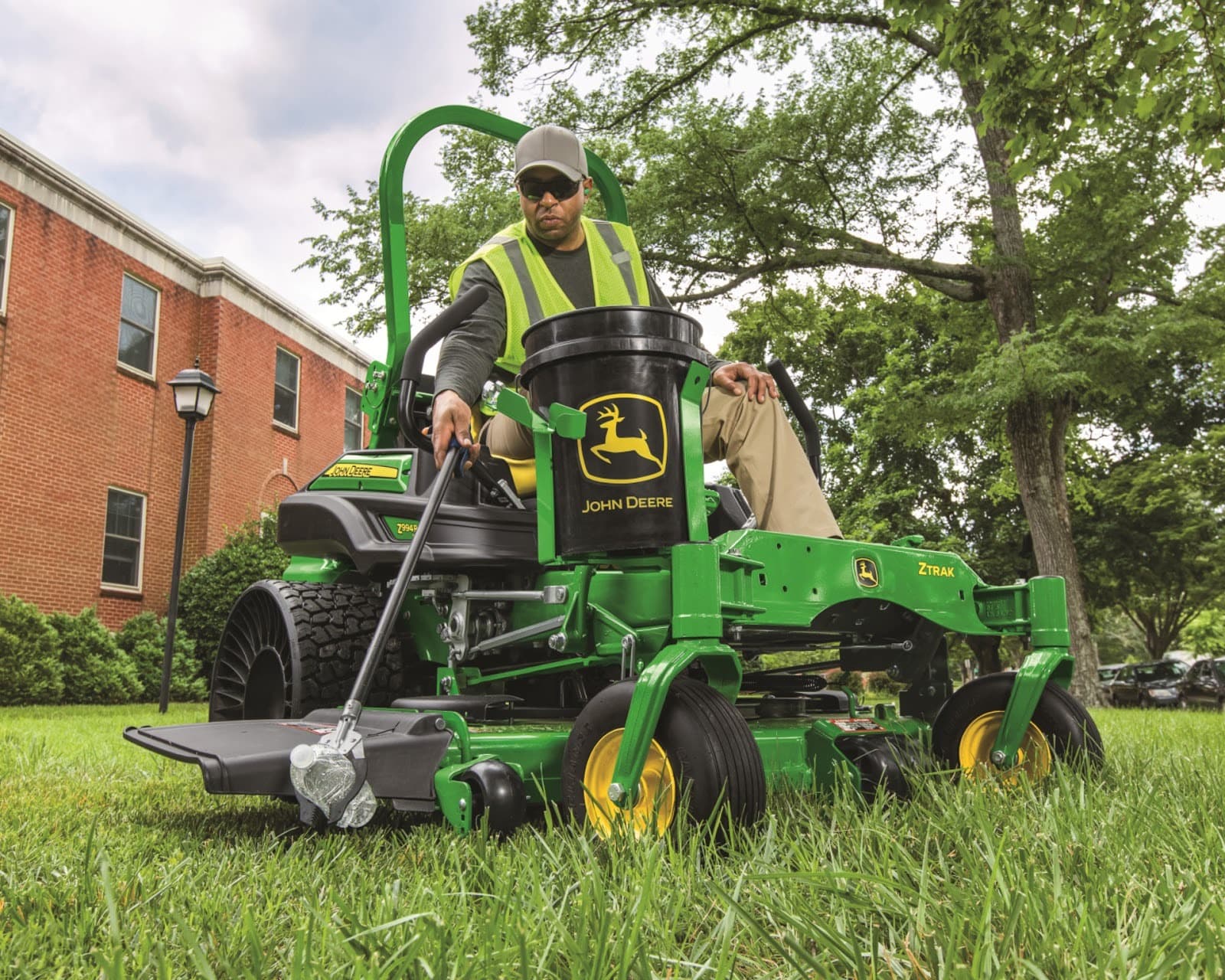 A worker operates a Z994R zero-turn mower to pick up trash on a property.