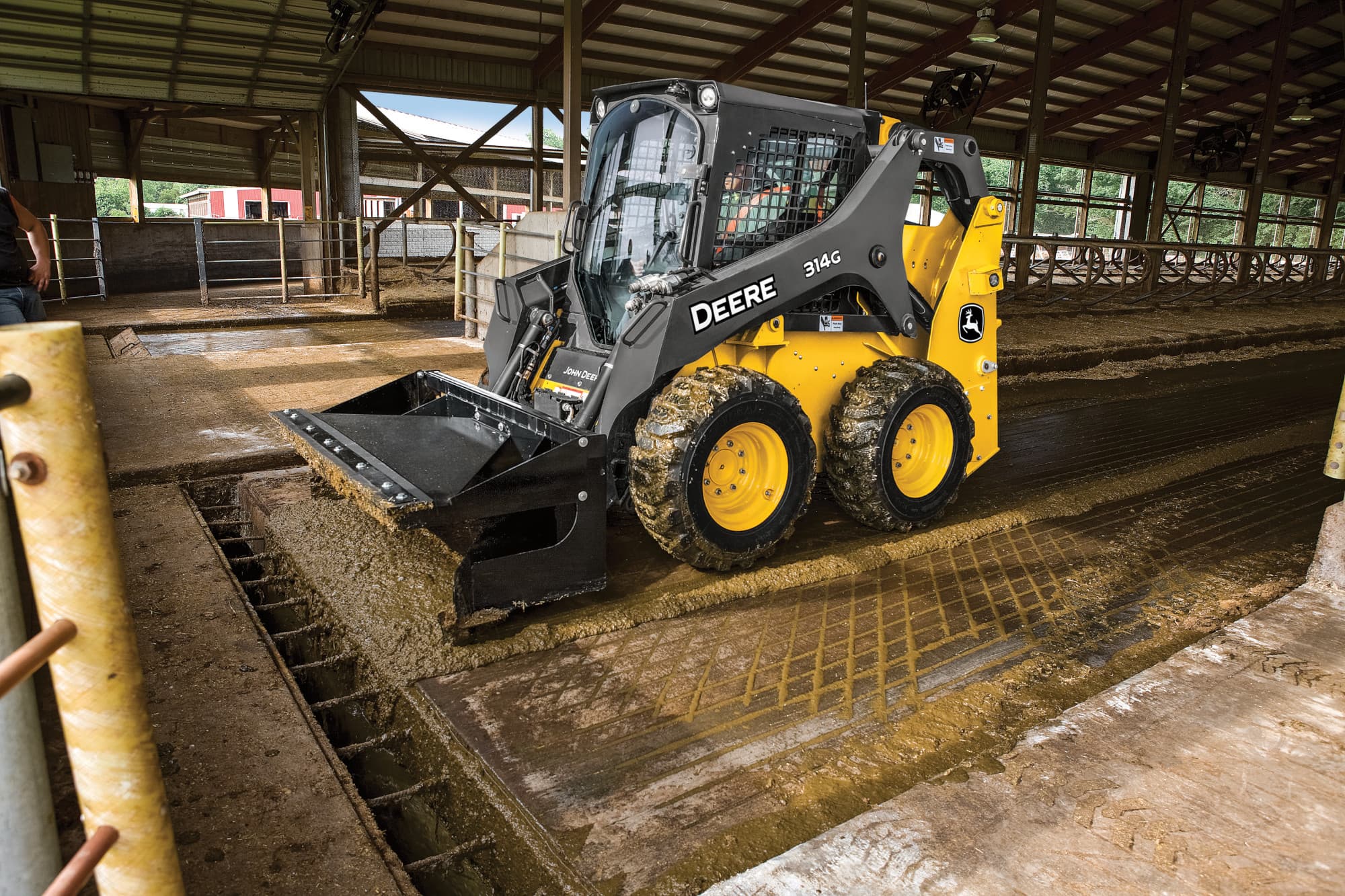 A 314G skid steer uses an attachment to level a dirt floor.