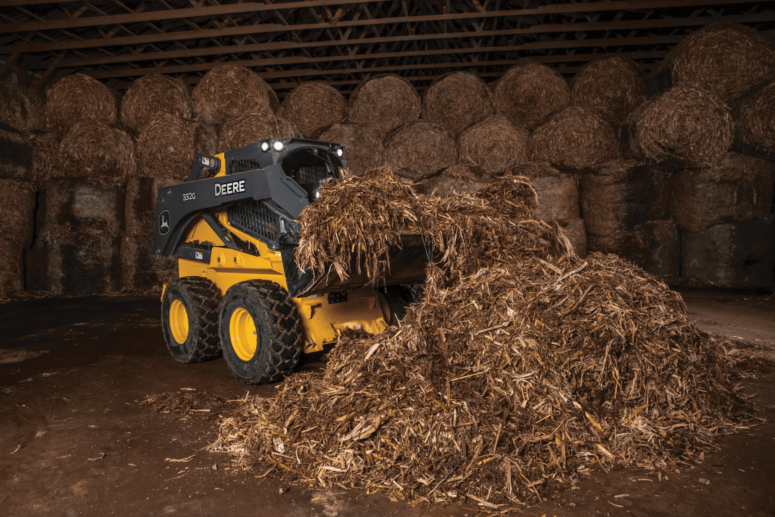 A 332G skid steer moves hay on a farm.